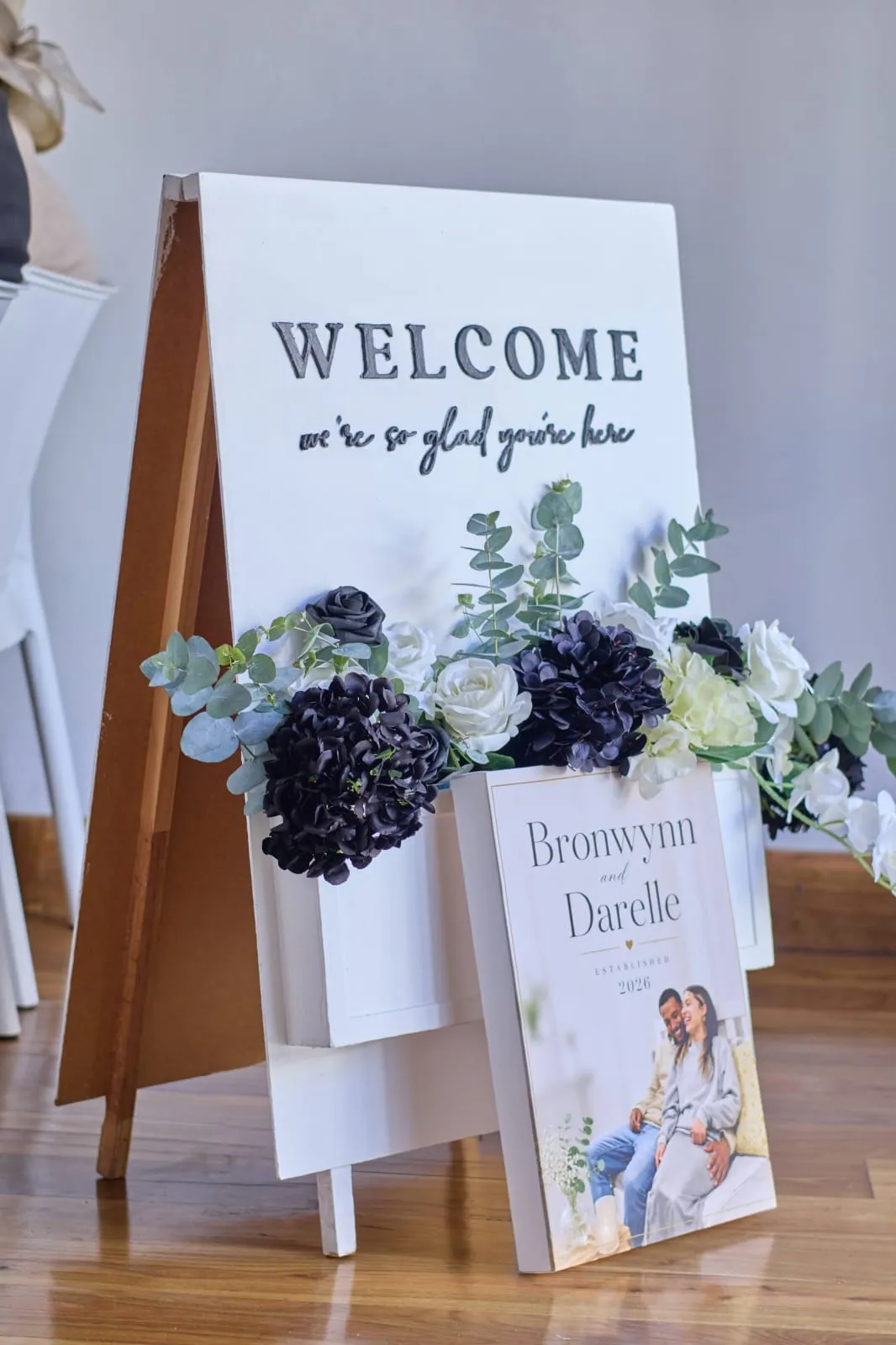 A welcome sign on an easel flanked by florals